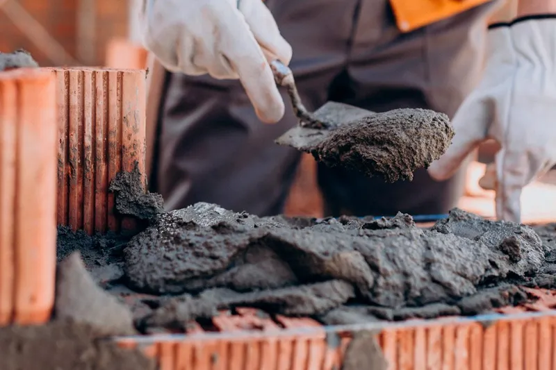 Albañil colocando ladrillos con llana en una obra en construcción