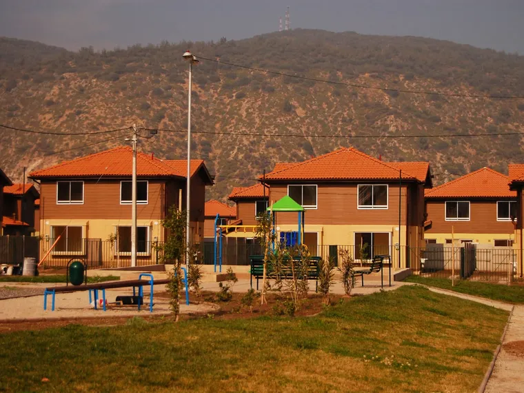Barrio de casas con plaza de juegos y cerro de fondo en Chile